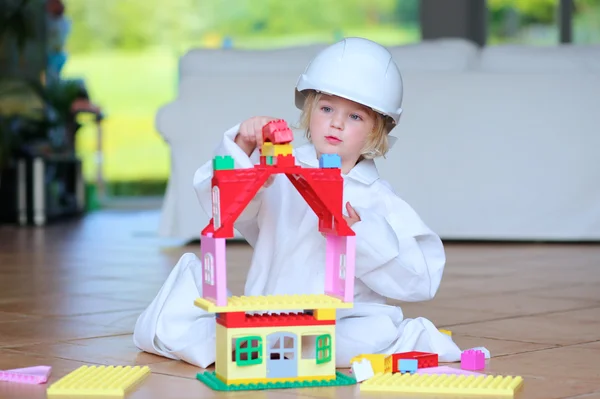 Toddler girl wearing safety helmet playing with building blocks — Stock Photo, Image