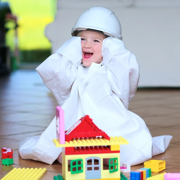 Menina criança vestindo capacete de segurança brincando com blocos de construção — Fotografia de Stock