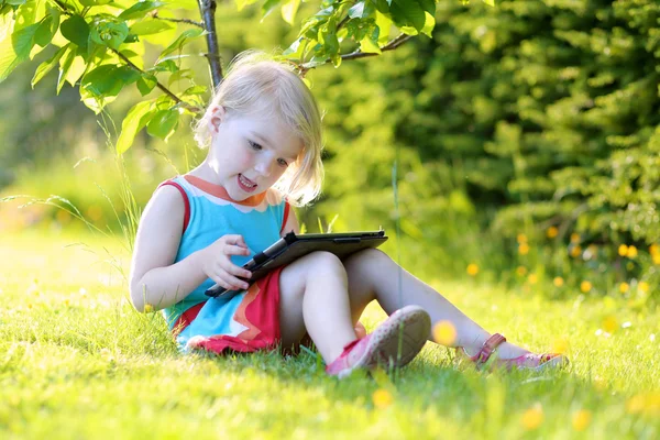 Toddler girl using tablet pc outdoors — Stockfoto
