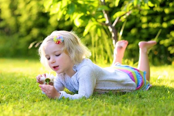 Pequeño niño jugando en el jardín acostado en la hierba — Foto de Stock