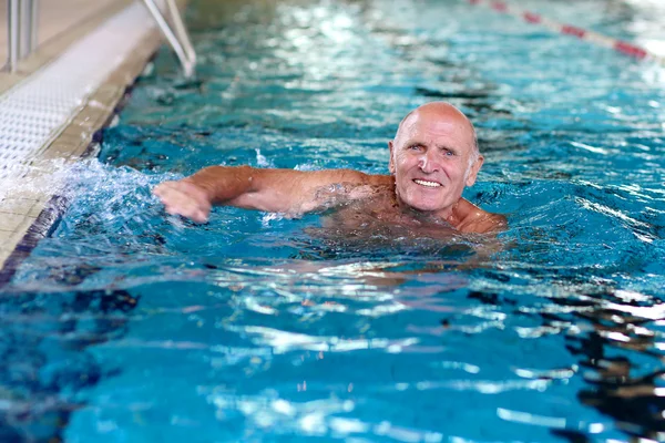 Uomo anziano attivo che nuota in piscina Foto Stock