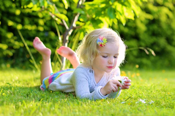 Little kid playing in garden lying in grass — Stock Image Little kid playing in garden lying in grass Stock Photo
