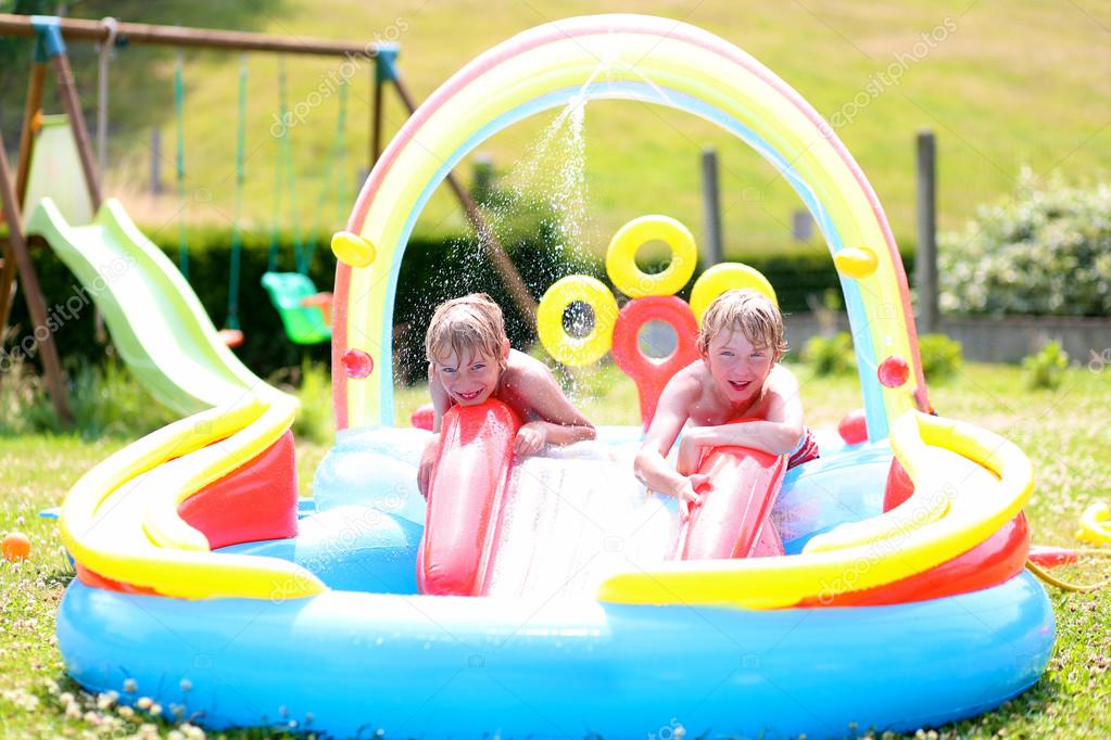 Kids enjoying inflatable swimming pool on summer day