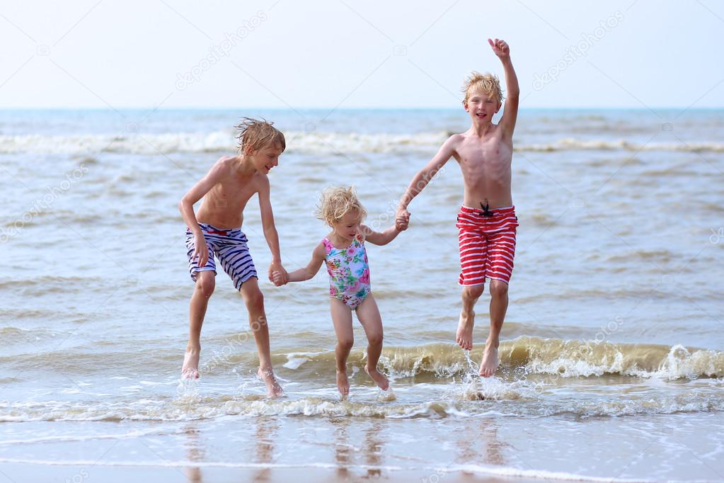 Kids having fun on the beach jumping over the waves