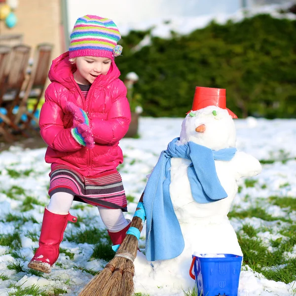 Niña pequeña jugando en el jardín cubierto de nieve — Foto de Stock