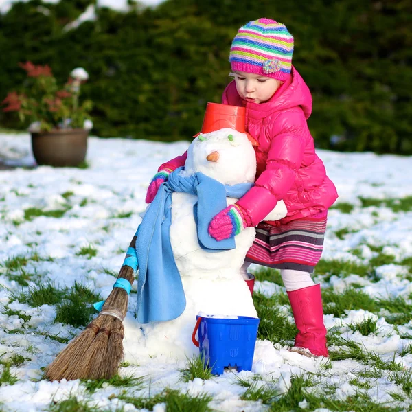 Niña pequeña jugando en el jardín cubierto de nieve — Foto de Stock