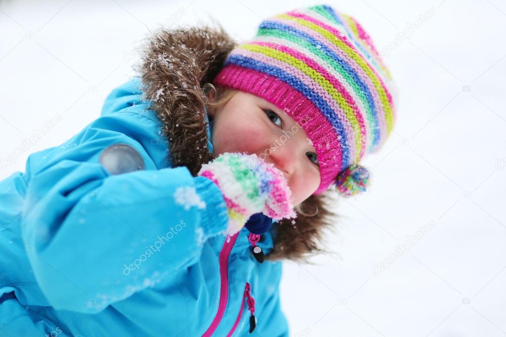 Adorable toddler girl playing in winter forest