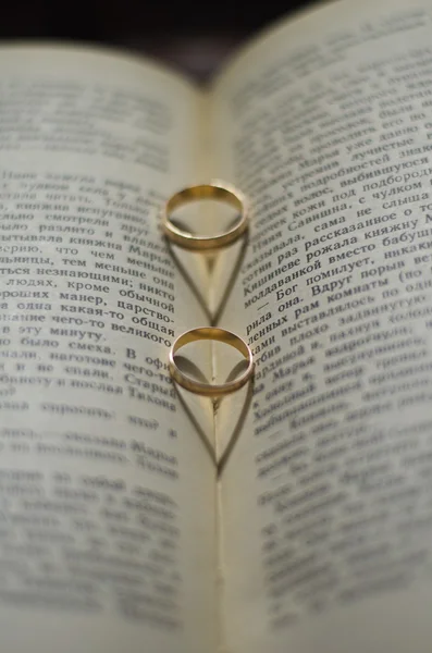 Anillos de boda de oro en un libro Corazón sombra — Foto de Stock