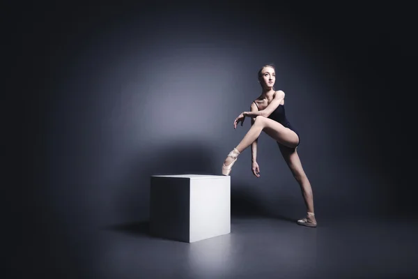 Young ballerina in dark cloth is dancing in a dark of the photostudio — Stock Photo, Image