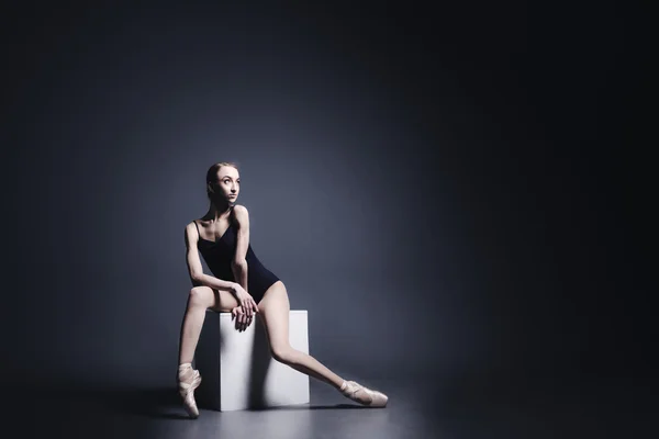 Young ballerina in dark cloth is dancing in a dark of the photostudio — Stock Photo, Image