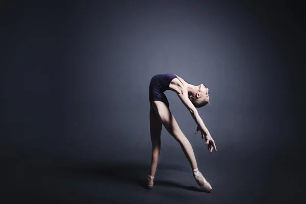 Giovane ballerina in tessuto scuro sta ballando in un buio del photostudio — Foto Stock