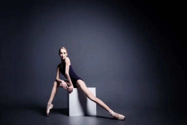Mladá baletka v tmavé látky tancuje v temnu fotostudia — Stock fotografie