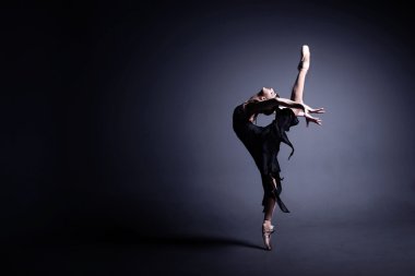 Karanlık bez içinde genç balerin photostudio karanlık bir dans ediyor
