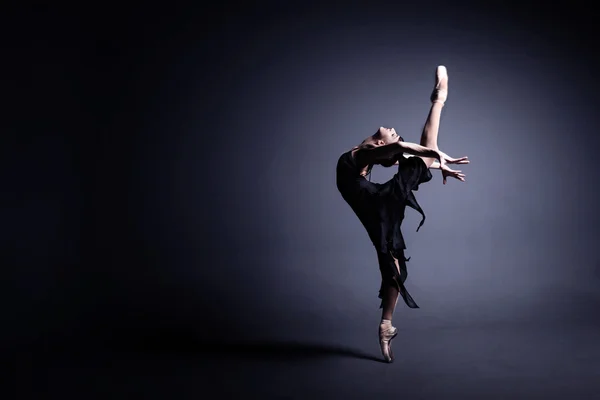 Joven bailarina en tela oscura está bailando en una oscuridad del fotoestudio — Foto de Stock