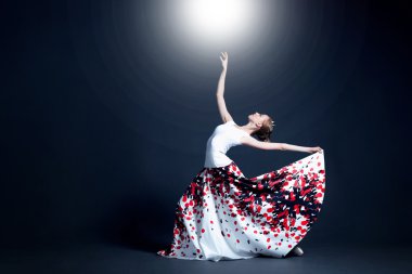 Young ballerina with a perfect body is dancing in the photostudio in different dresses