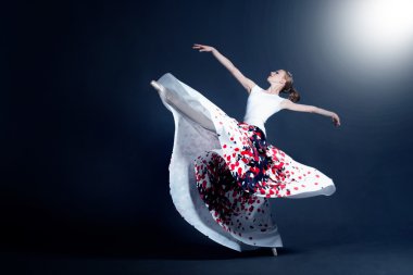 Young ballerina with a perfect body is dancing in the photostudio in different dresses