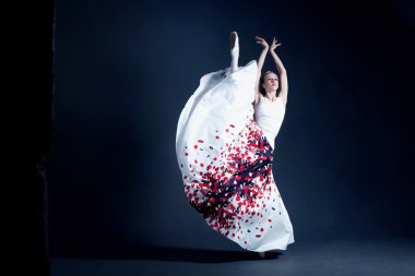 Young ballerina with a perfect body is dancing in the photostudio in different dresses