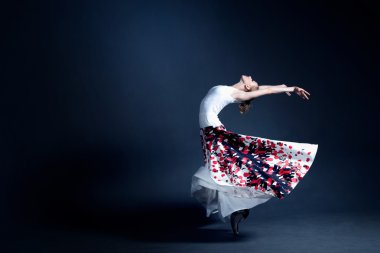 Young ballerina with a perfect body is dancing in the photostudio in different dresses