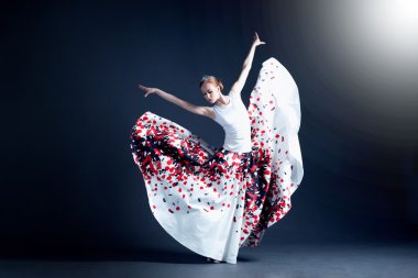 Young ballerina with a perfect body is dancing in the photostudio in different dresses