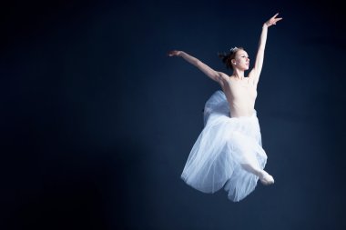 Young ballerina with a perfect body is dancing in the photostudio in different dresses