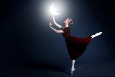 Young ballerina with a perfect body is dancing in the photostudio in different dresses