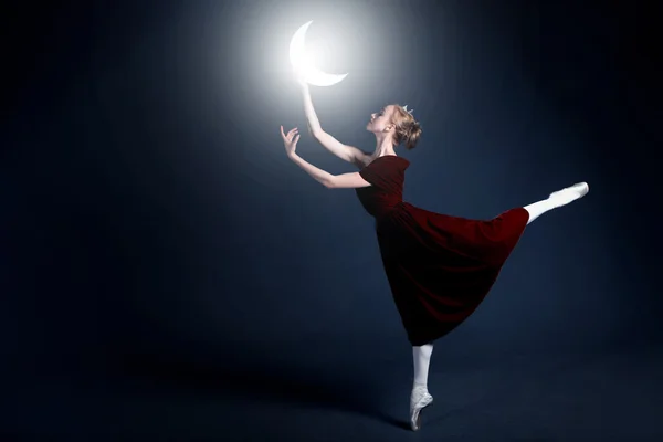 Молодая балерина с идеальным телом танцует в фотостудии в разных платьях — стоковое фото