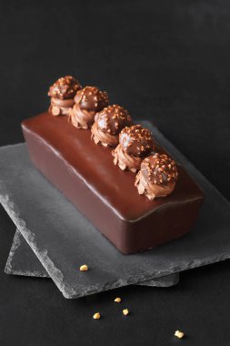 Çikolata kaplı fındıklı, fındıklı, kremalı, çikolatalı Ganache ve Praline mantarlı, koyu bir arka planda..