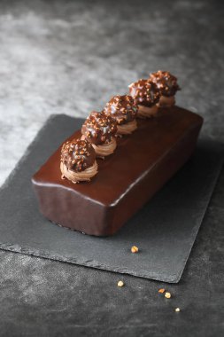 Çikolata kaplı fındıklı, fındıklı, kremalı, çikolatalı Ganache ve Praline mantarlı, koyu bir arka planda..