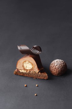 Çağdaş Çikolatalı Mousse Pastası ile Craquelin Choux Pastası, çikolata aynası jöleli, koyu bir arka planda..