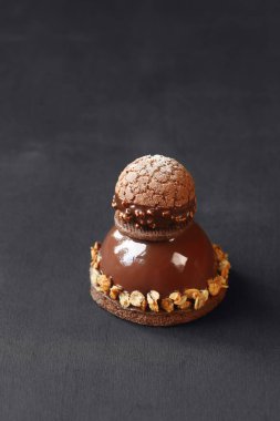 Çağdaş Çikolatalı Mousse Pastası ile Craquelin Choux Pastası, çikolata aynası jöleli, koyu bir arka planda..