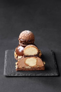 Çağdaş Çikolatalı Mousse Pastası ile Craquelin Choux Pastası, çikolata aynası jöleli, koyu bir arka planda..