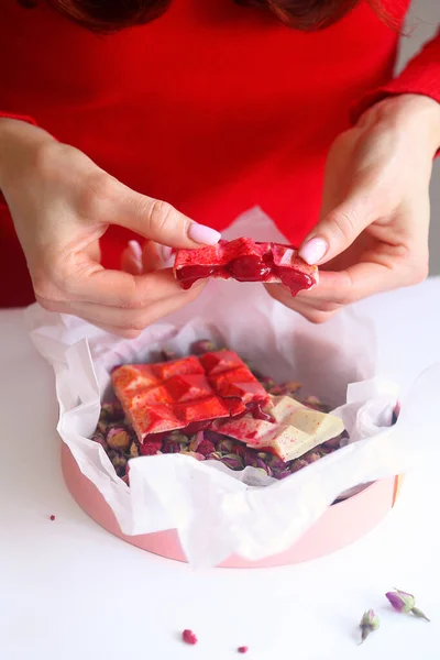 Homemade White Chocolate Bar with liquid Raspberry Filling, in a gift box with dried rose buds, on a white background.