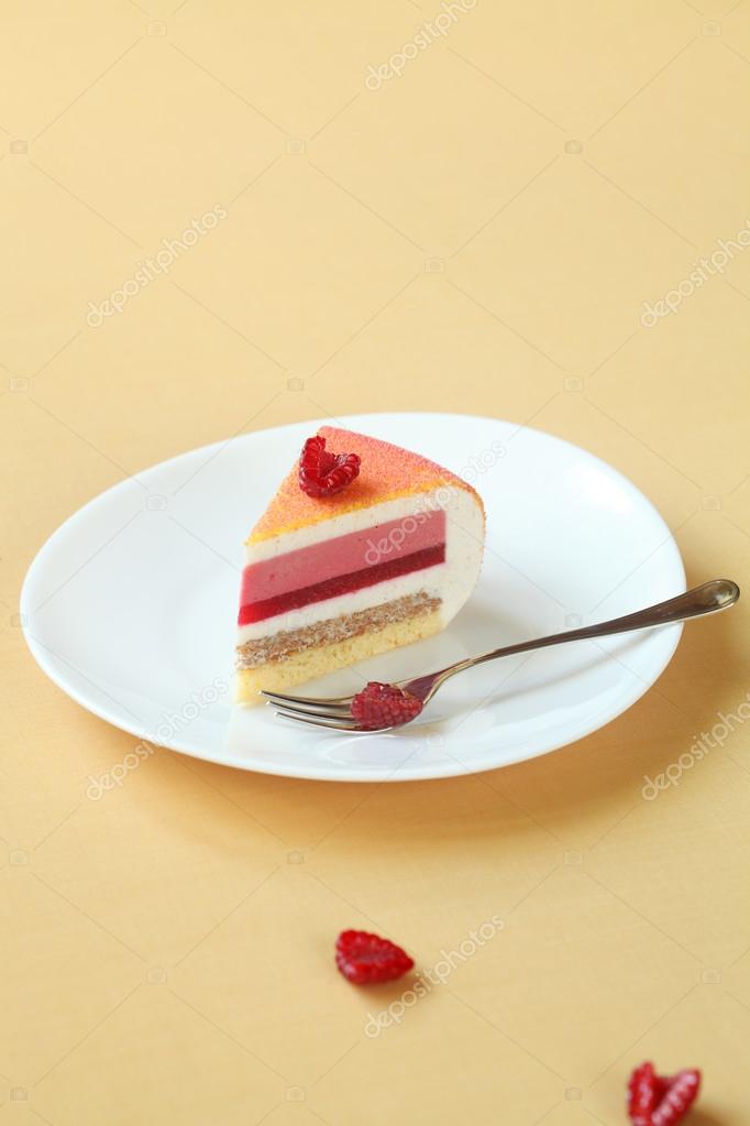 Piece of Layered Vanilla, Raspberry, Peach Mousse Cake, covered with colored velvet spray