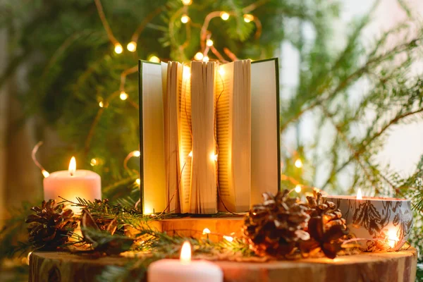 open book on winter background with lights and candles
