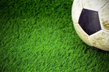 Suni çim alan üzerinde eski püskü futbol topu.
