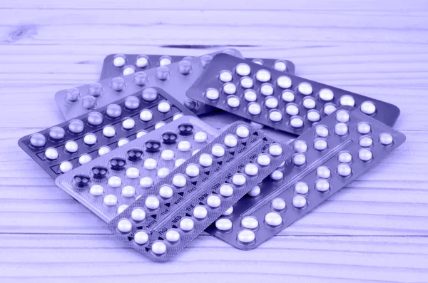 Orális fogamzásgátló tabletta csíkok a fenyő fa asztal. — Stock Fotó