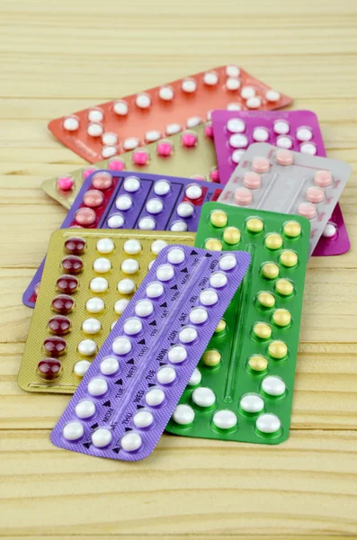 Kleurrijke mondelinge Contraceptieve Pil stroken op pine houten tafel. — Stockfoto