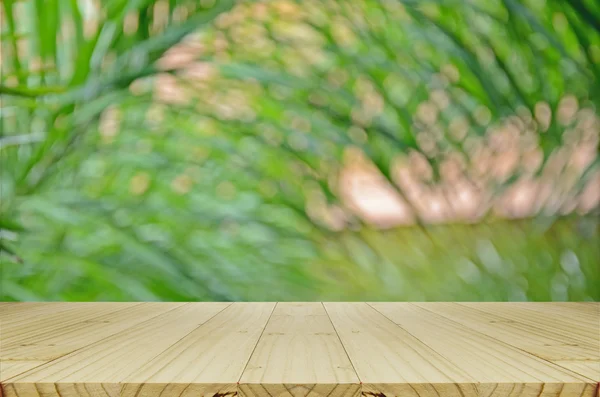 Liście palmowe nieostre tło z drewnianym stołem. — Zdjęcie stockowe