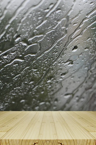 Gotas de chuva em fundo de janela de vidro com mesa de madeira . — Fotografia de Stock