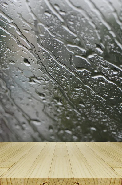 Gotas de chuva em fundo de janela de vidro com mesa de madeira . — Fotografia de Stock