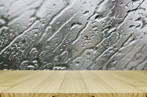 Gotas de chuva em fundo de janela de vidro com mesa de madeira . — Fotografia de Stock