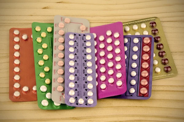 Barevné orální Antikoncepční pilulka proužky na borové dřevo stůl. — Stock fotografie