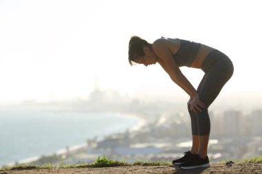 Kenar mahallelerde spordan sonra dinlenen yorgun bir koşucunun yan görünüm portresi