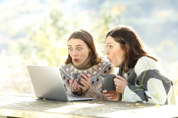 Amigos Sorprendidos Invierno Comprobando Portátil Sentado Banco — Foto de Stock