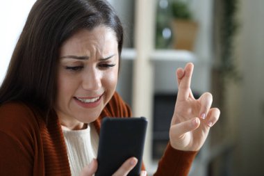 Sinirli kadın evde cep telefonundan haber bekliyor.