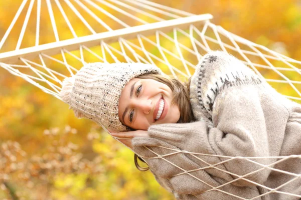 満面の笑みを浮かべて幸せな女性とともにハンモックで休んでいる秋の森の中でカメラを見て — ストック写真