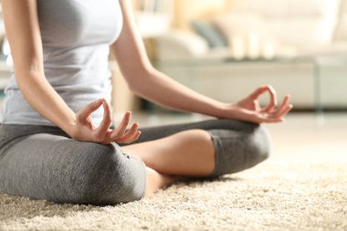 Evdeki halıda yoga yapan bir kadın eli.