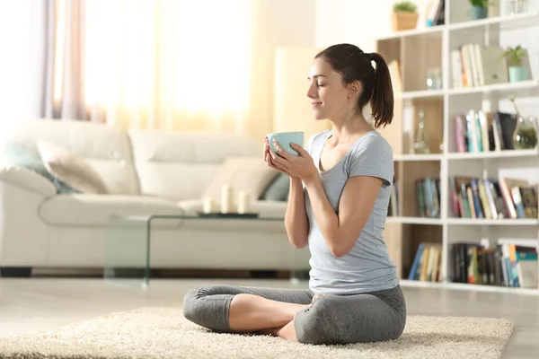 Yoga egzersizlerinden sonra evde yerde oturup çay içen Yogi.