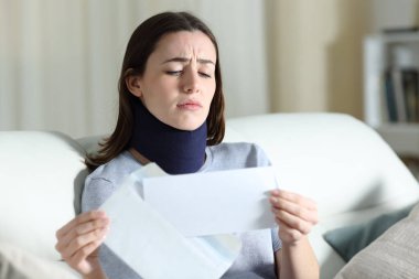 Üzgün engelli kadın mektupta kötü haber okuyor. Evdeki oturma odasında bir kanepede oturuyor.