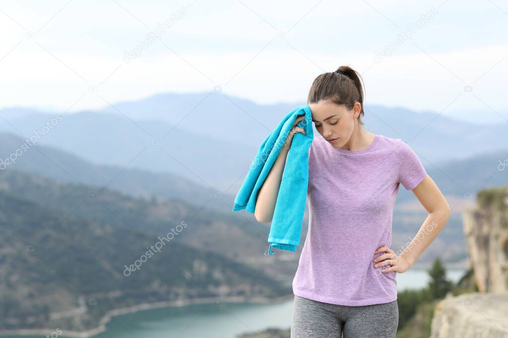 Tired runner drying sweat after sport walking in the mountain